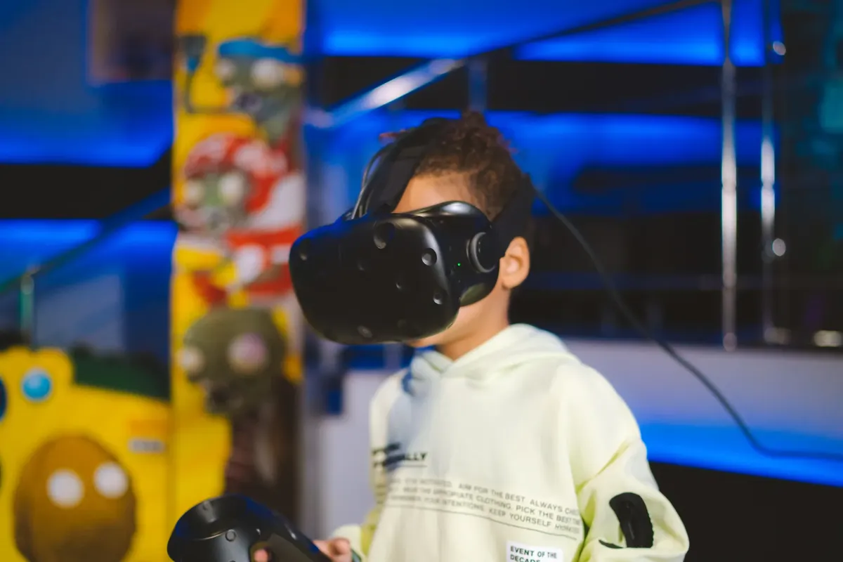 A young child playing with virtual reality goggles indoors, immersed in a gaming experience.